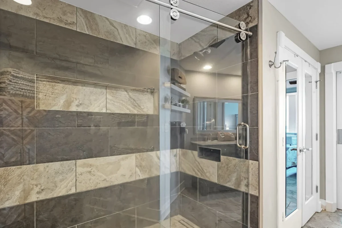 Gulf Shores walk-through shower with gray and tan tile and a glass door